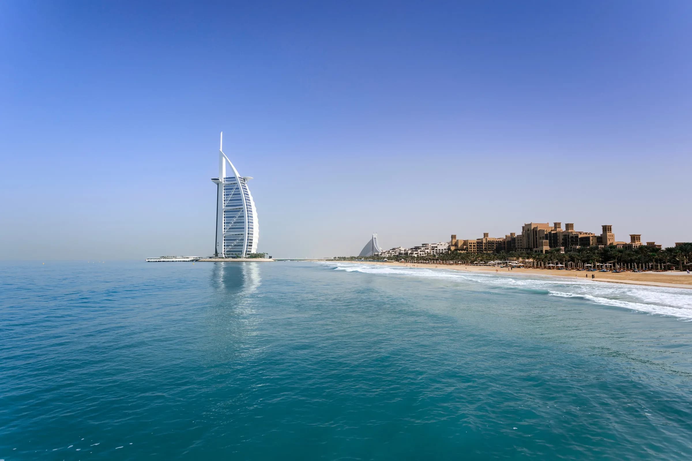 The Burj Al Arab rising from the Arabian Gulf under a clear blue sky