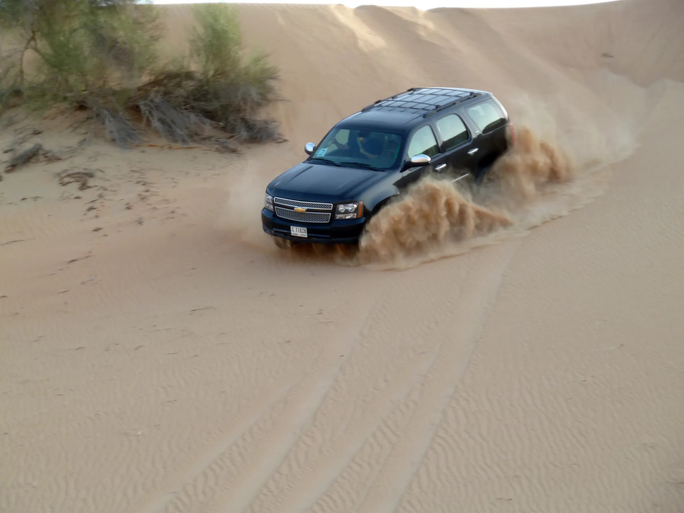 A 4x4 kicking up sand while dune bashing on a Dubai desert safari