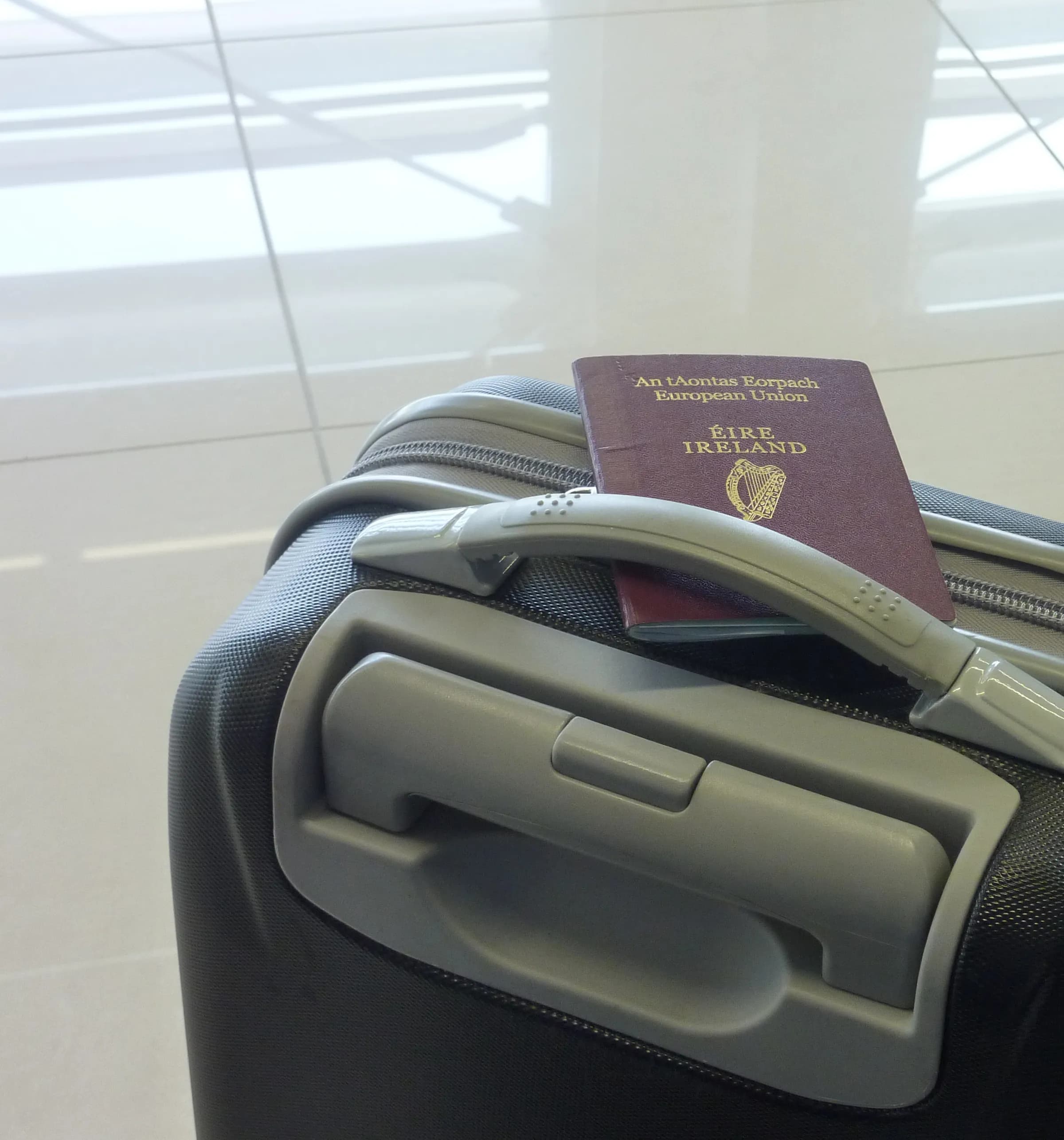 A passport resting on a suitcase handle at the airport