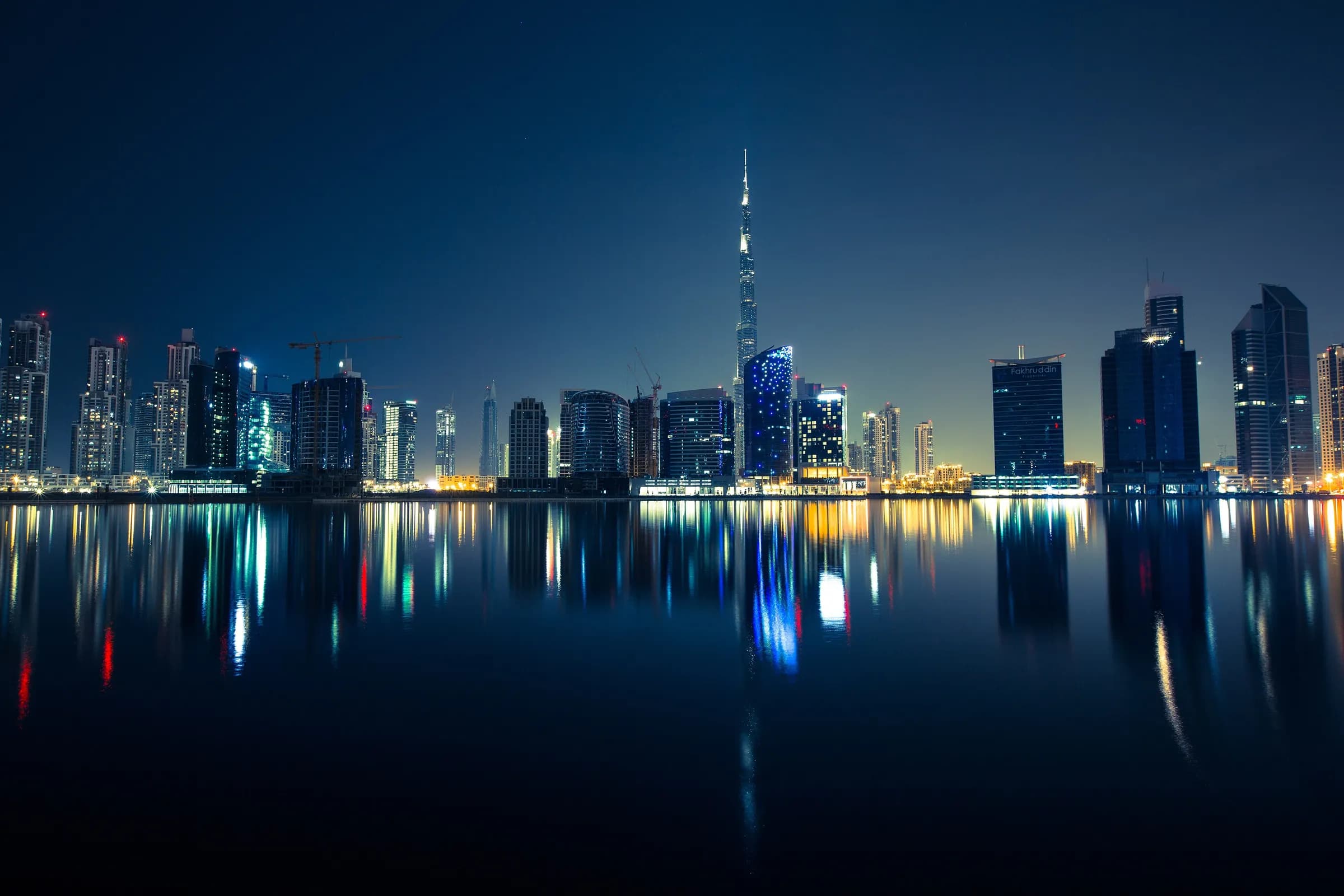 The Dubai skyline and Burj Khalifa reflected in the water at night